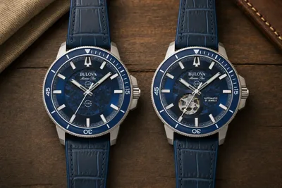 Dois Bulova Marine Star lado a lado sobre madeira escura, um com janela de movimento e outro de mostrador fechado