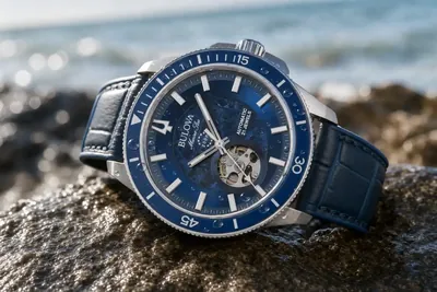 Bulova Marine Star de mostrador azul sobre pedra molhada, com a pulseira de aço à vista