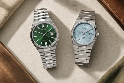 Citizen Tsuyosa verde e Tissot PRX azul-claro lado a lado sobre pedra clara, os dois com pulseira integrada