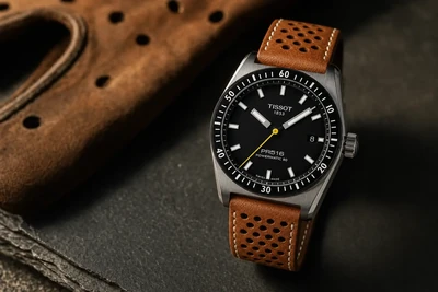 Tissot PR516 de mostrador preto e pulseira de couro marrom perfurada sobre pedra escura