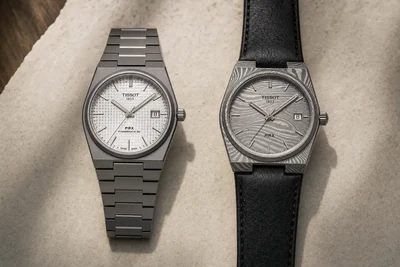 Tissot PRX de titânio e Tissot PRX em aço damasco lado a lado sobre pedra clara